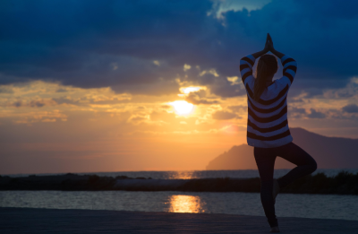 Sonnenuntergang am Meer, Frau im Vordergrund in Yoga-Figur, Yoga-Genuss